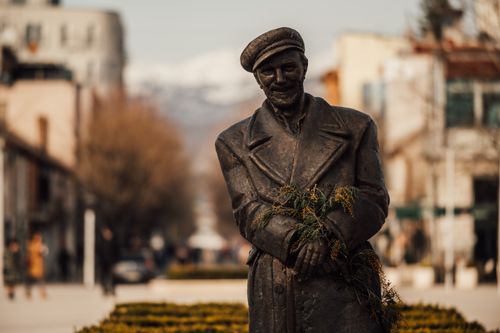Free A bronze statue of a man with flowers on a street in Niksic, Montenegro, with distant mountains. Stock Photo