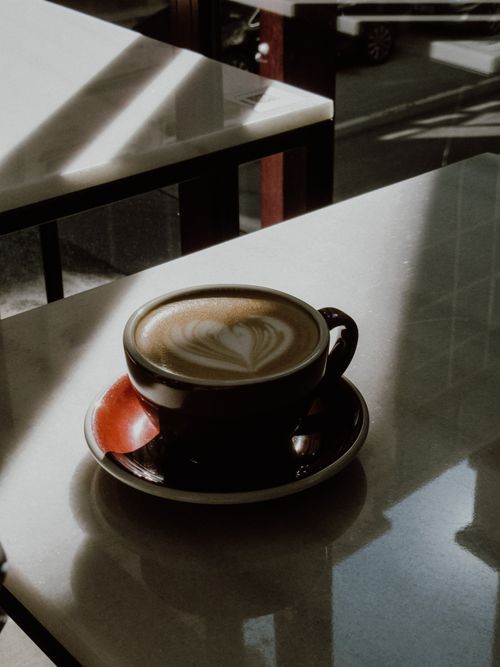 Free A warm cup of coffee featuring delicate latte art, set on a sun-drenched café table in Istanbul. Stock Photo