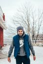 Man in Black Jacket and Black Knit Cap Standing Near Red Building