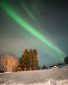 Aurora Borealis lights up the night sky over a snowy landscape in Troms og Finnmark, Norway.