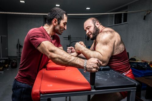 Free Two men engage in intense arm wrestling in a gym, showcasing strength and masculinity. Stock Photo
