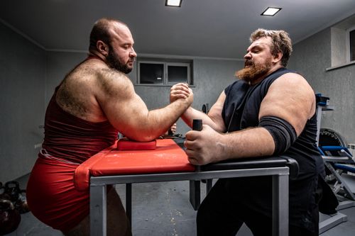 Free Two muscular men in a gym engage in a face-to-face arm wrestling match. Stock Photo