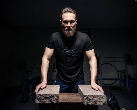 Strong bearded man in a dimly lit gym, conveying intense focus and power.