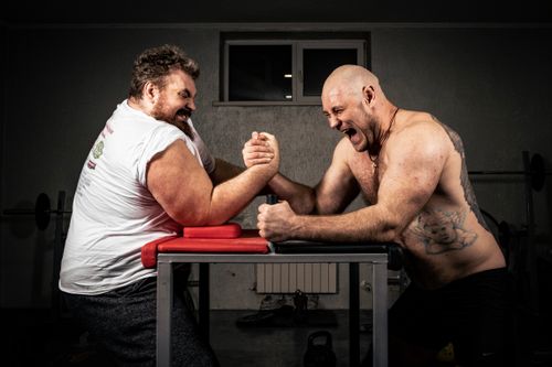 Free Two men engaged in a heated arm wrestling match showcasing strength and determination. Stock Photo