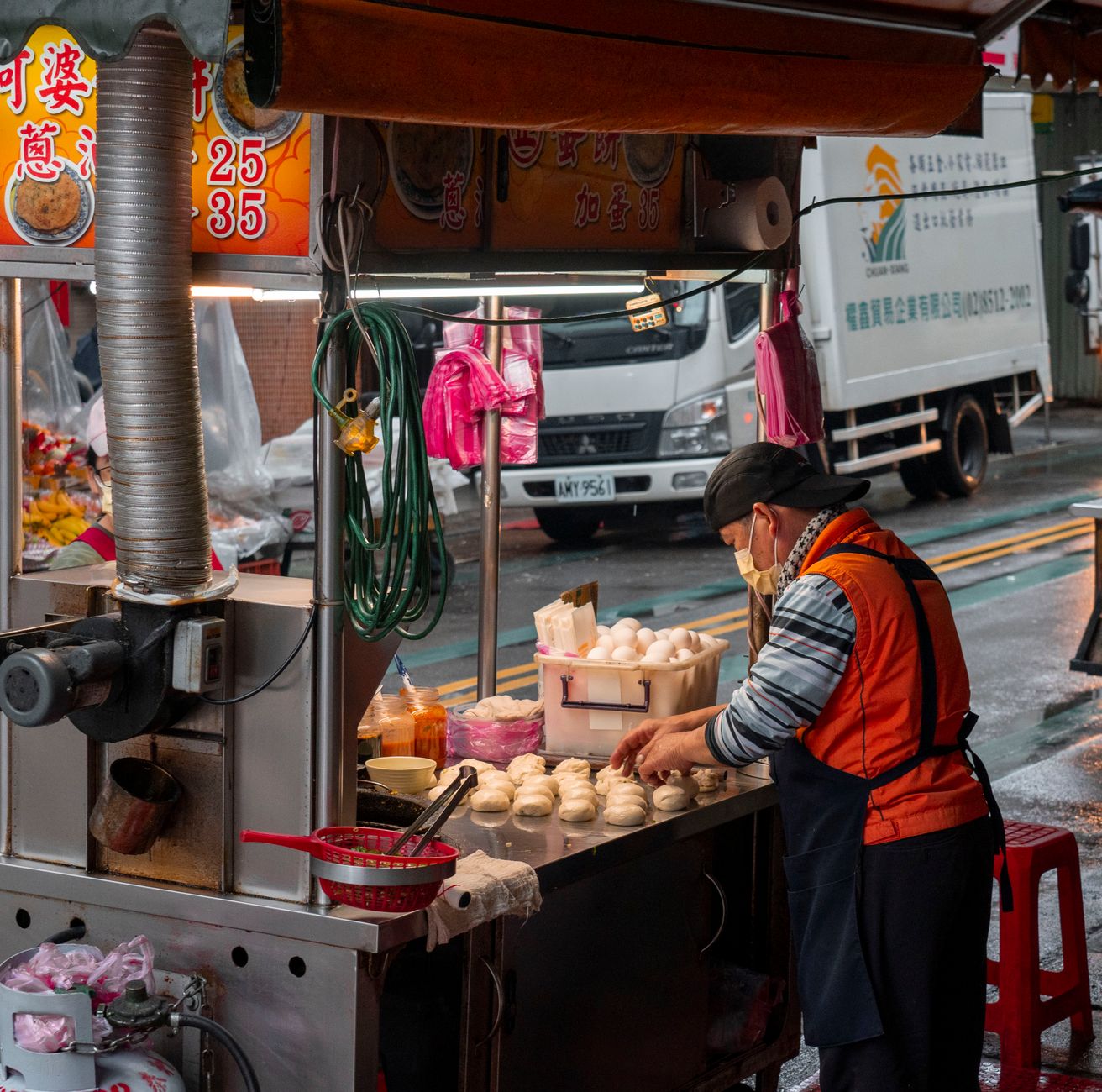A street vendor prepares traditional dumplings at an urban food stall, showcasing a bustling city atmosphere.