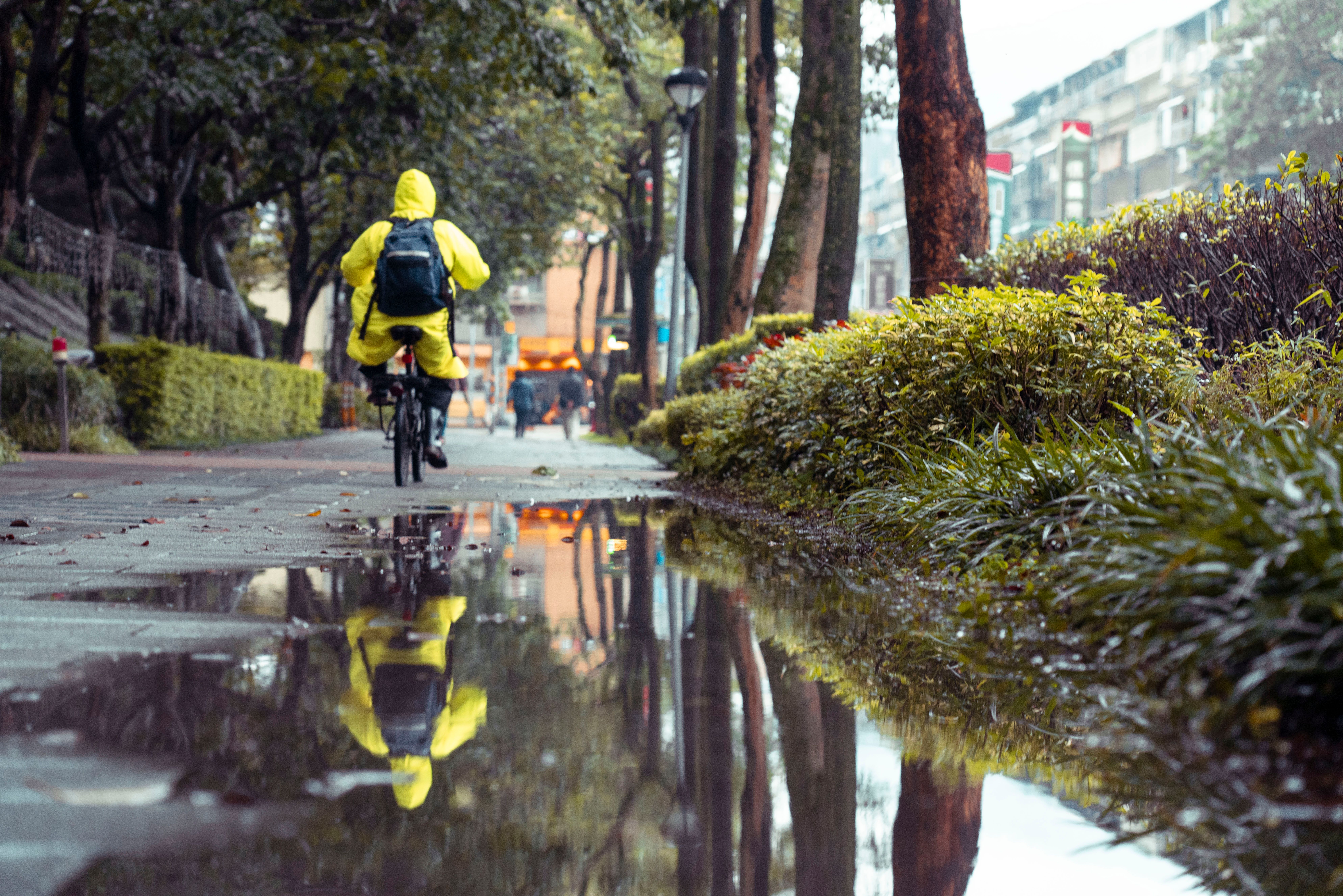 Cyclist in a rain cape crossing a bridge in Utrecht on a wet grey day