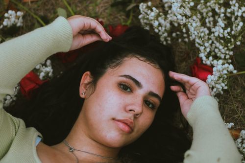 Free Portrait of a woman lying on grass with roses and baby's breath Stock Photo