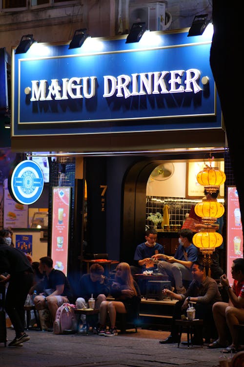 People Sitting on Steps of Drink Bar at Night