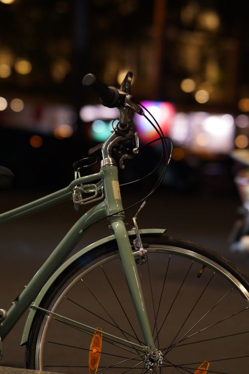 Free A parked bicycle with a shiny frame and wheel captured during the night on a city street. Stock Photo