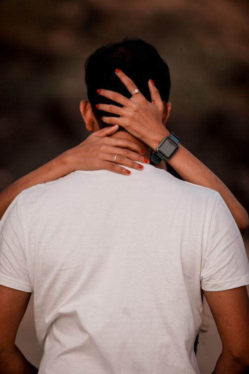 Free Back view of a couple embracing, focusing on hands around neck. Romantic and intimate moment. Stock Photo