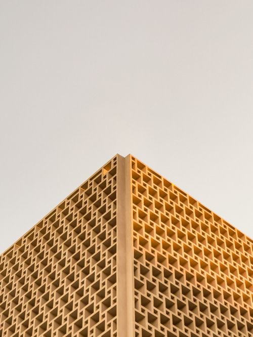 Free A striking low angle view of a geometric building facade at sunrise, highlighting patterns and textures. Stock Photo