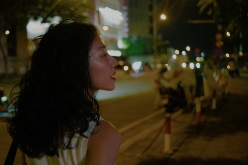 Free A woman walks along a city street at night, illuminated by streetlights. Stock Photo