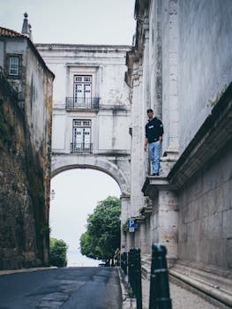 一名男子在风景如画的葡萄牙里斯本探索历史悠久的街道拱门