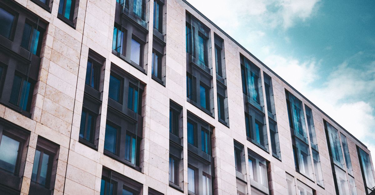 Modern apartment building facade with glass windows against a blue sky in Frankfurt.