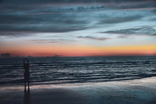 Schattenbild Der Person An Der Küste Während Der Goldenen Stunde