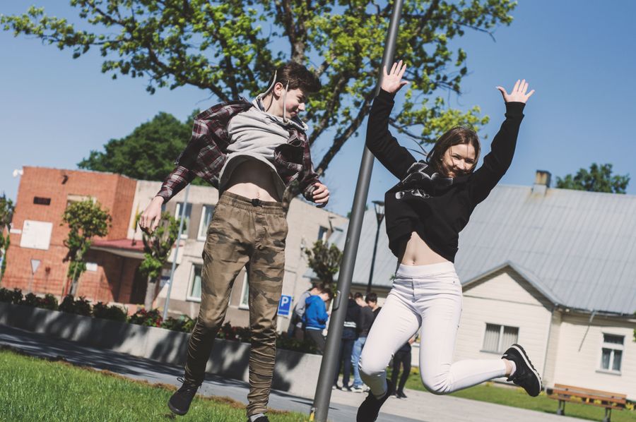 Dva středoškoláci radostně skáčou před školou