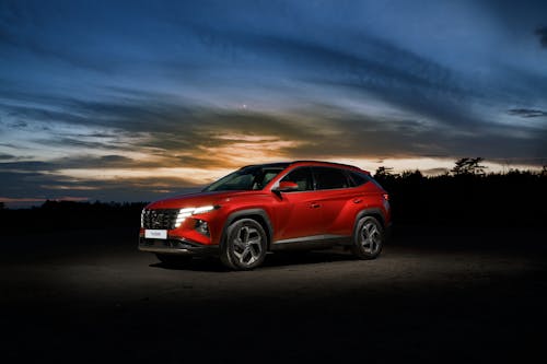 Red Car on Gray Asphalt Road during Sunset