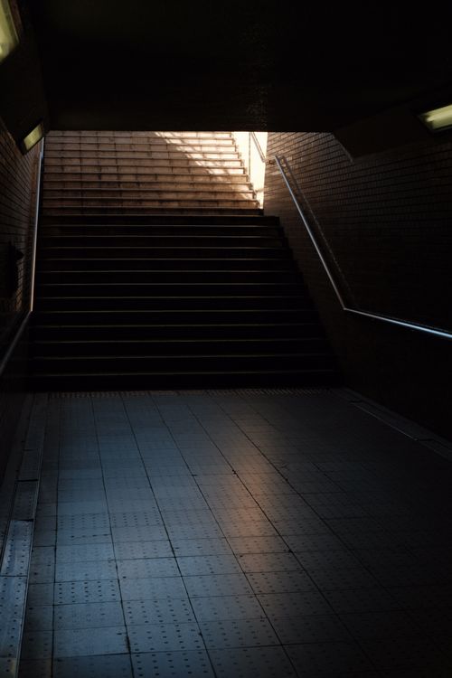 Free A dark underground staircase with metal railings and a passage leading to the light. Stock Photo
