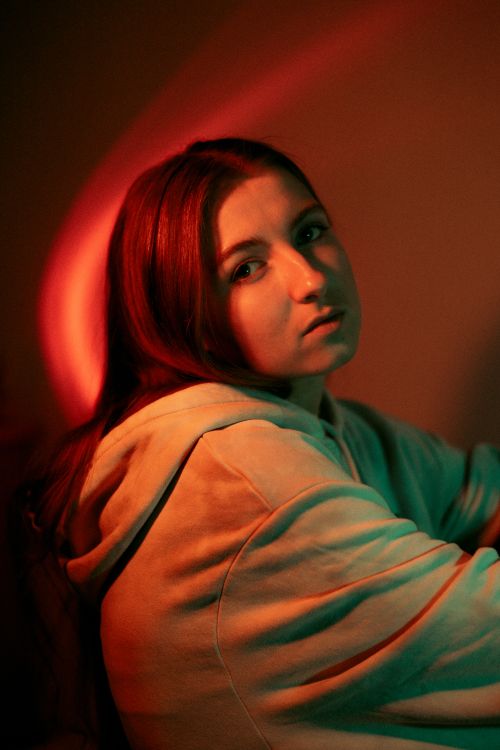 Free Portrait of a woman in a hoodie with moody lighting, conveying introspection and depth. Stock Photo