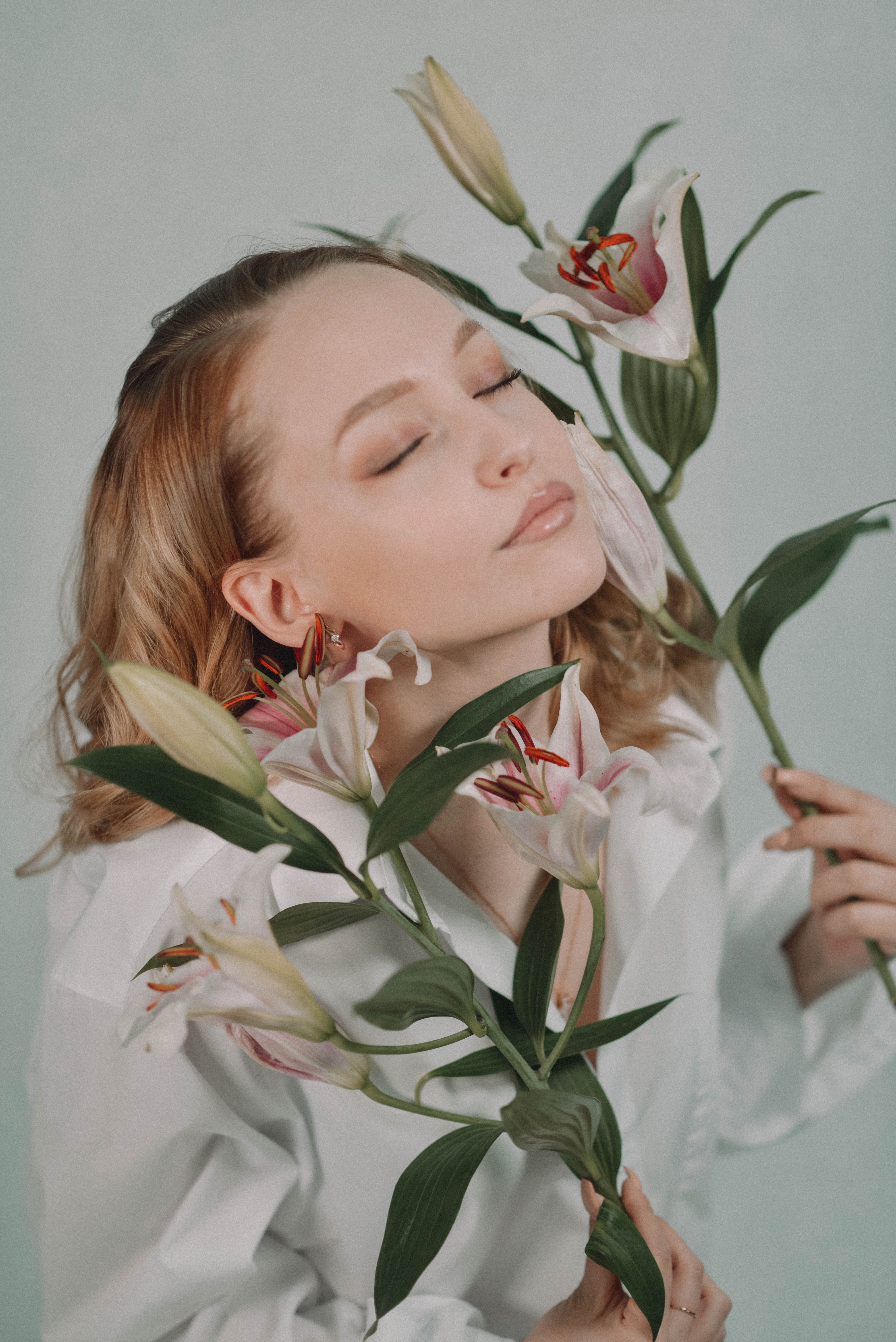 A Woman with Her Eyes Closed Holding Lily Stems · Free Stock Photo