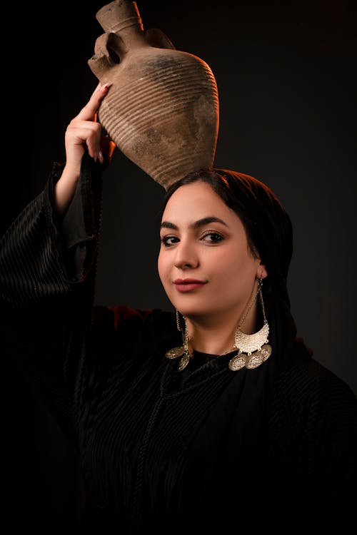 Young Woman Holding Vase on Her Head 
