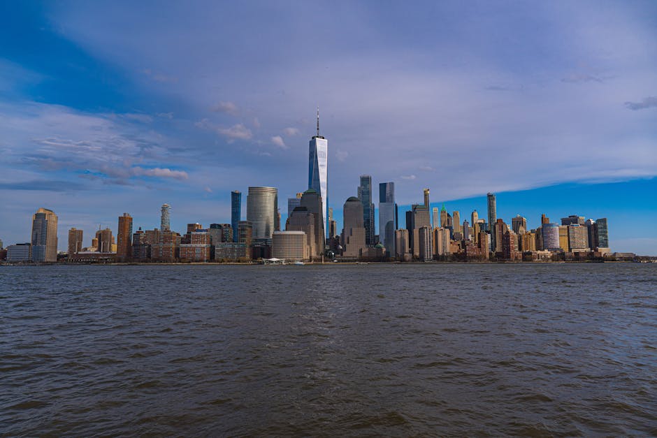 Panoramic view of New York City skyline featuring One World Trade Center under a clear blue sky