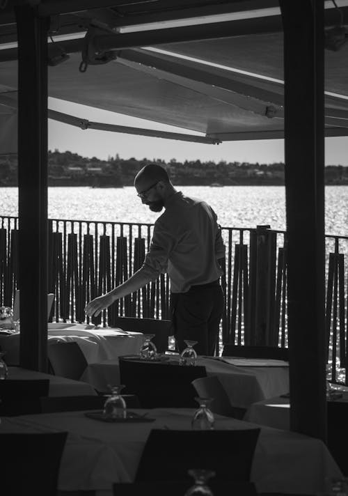 Grayscale Photo of a Man Fixing Tables