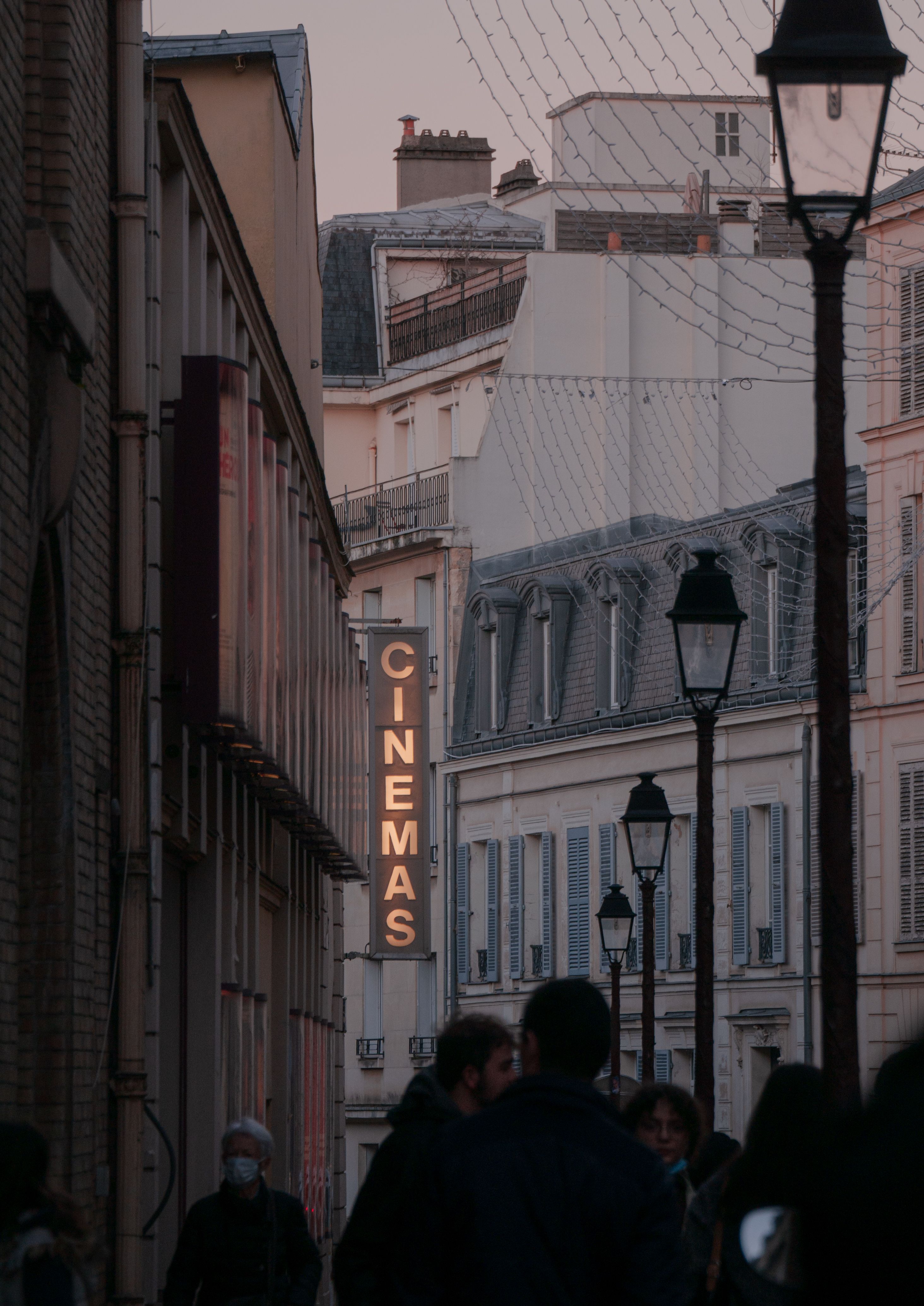 A picturesque view of a Parisian street with cinema sign and classic architecture at twilight.