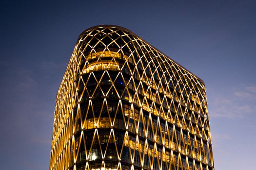 A striking modern skyscraper with illuminated geometric patterns against a twilight sky.