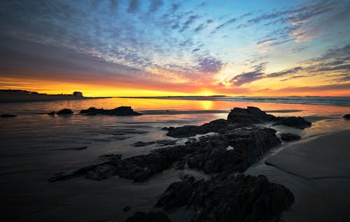 Free A Rocky Shore Under the Cloudy Sky During Sunrise Stock Photo