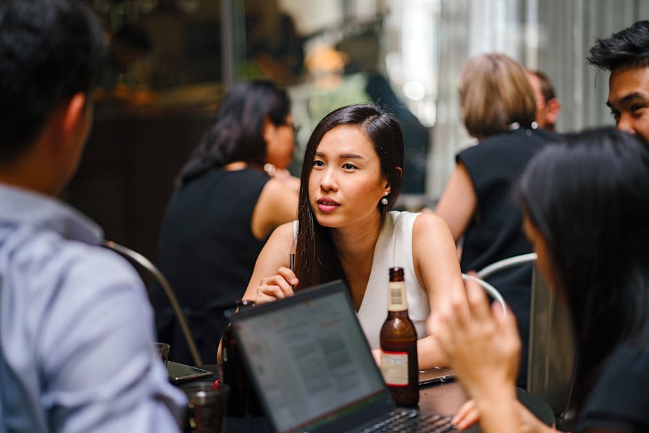 Woman Wearing White Top Sitting Near Table With People