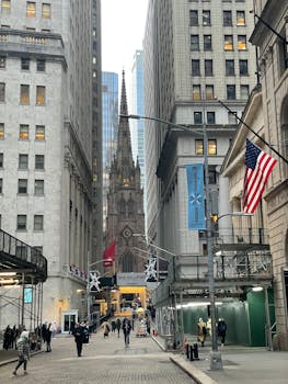 A bustling urban street view in Manhattan featuring the iconic Trinity Church with people and skyscrapers.