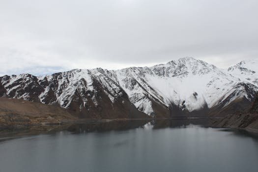 Tranquil snowy mountains reflecting in a serene lake at Yerbas Buenas, Chile.