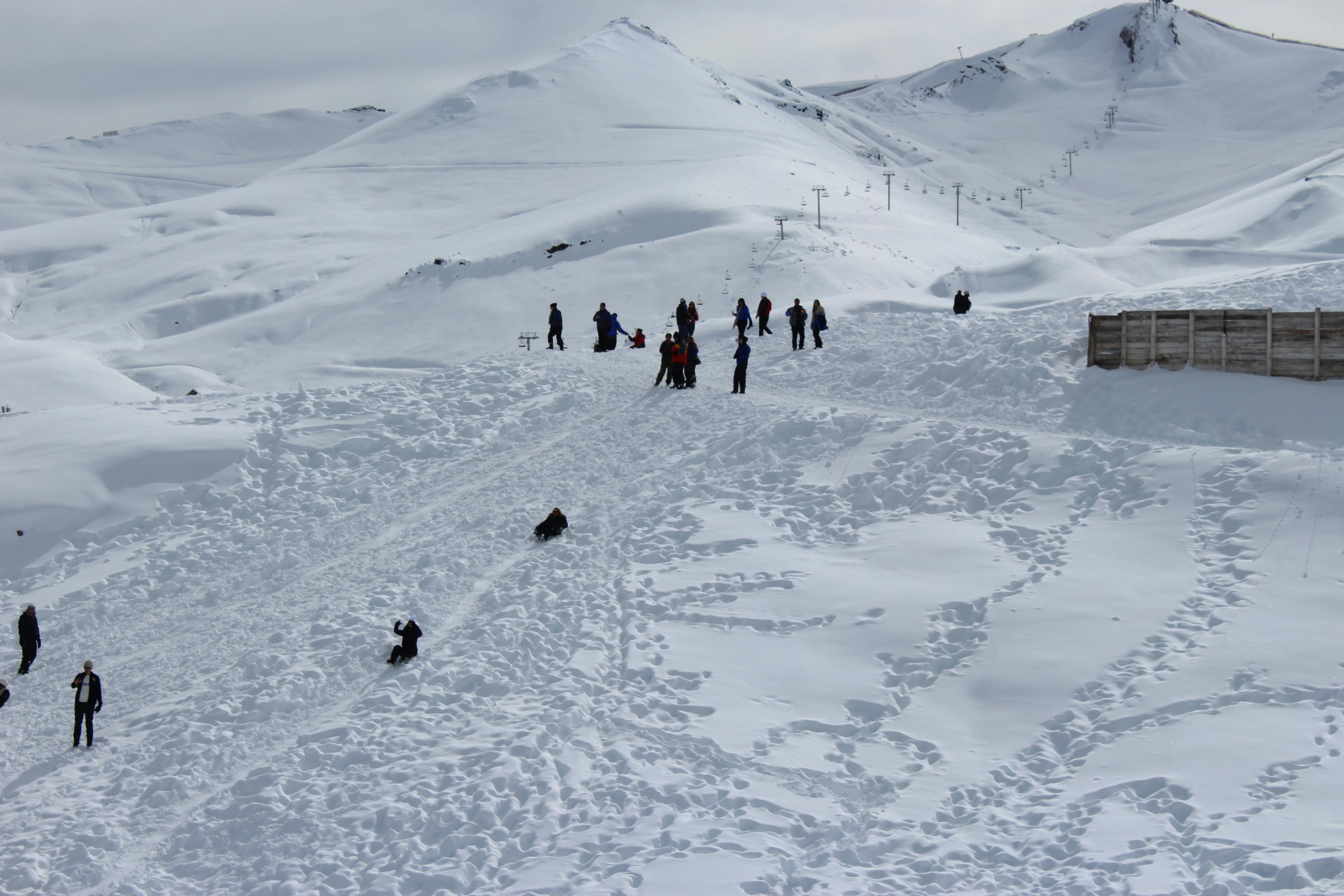 Prescription Goggle Inserts - People enjoying a snowy mountain slope with sledding and scenic winter views.