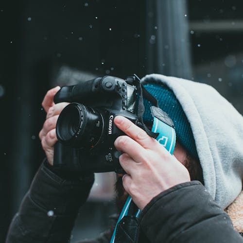 Free A Person in Black Jacket Taking Picture Under the Snow Stock Photo