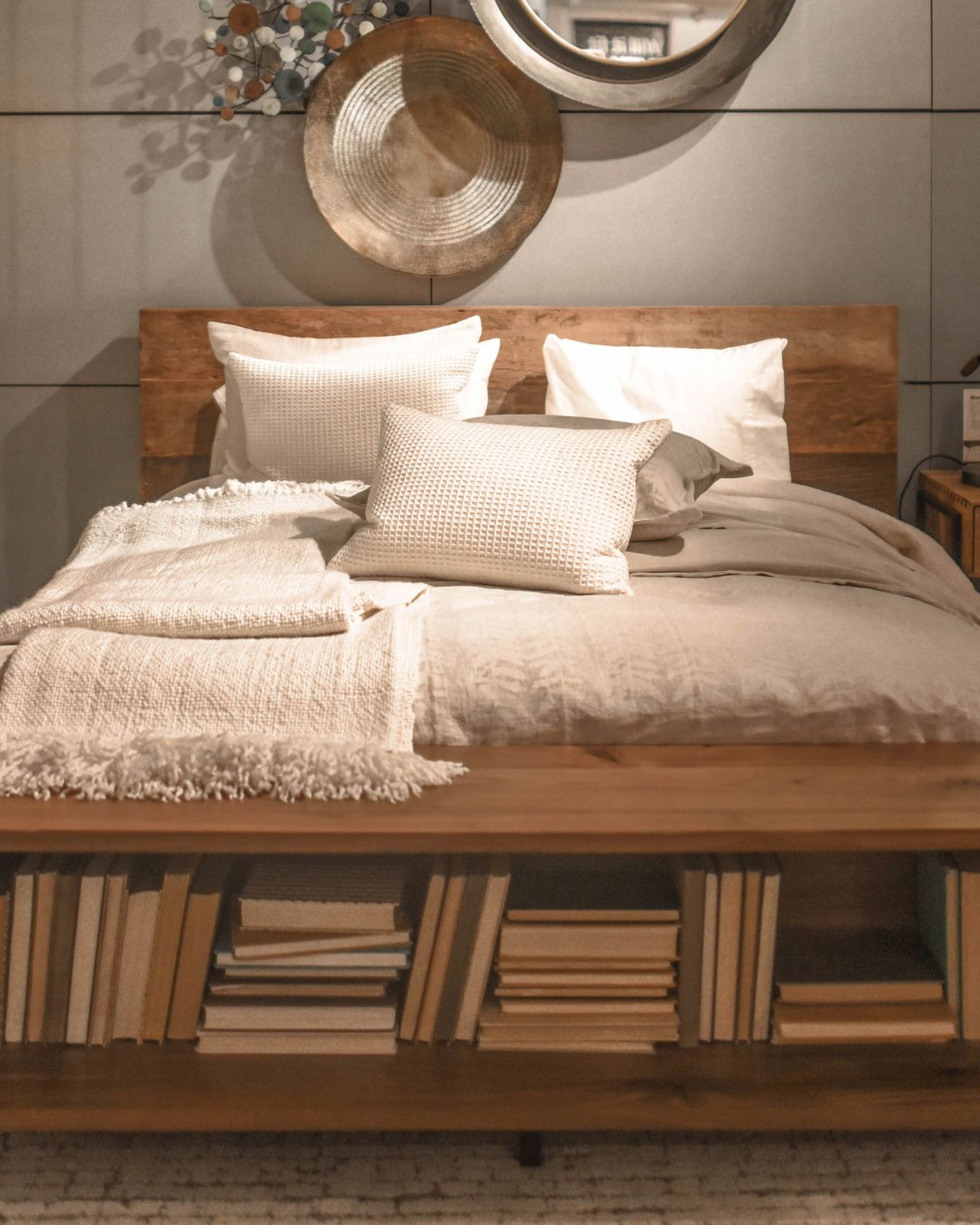 Wooden bed with a bookcase footboard filled with books at the foot of the bed