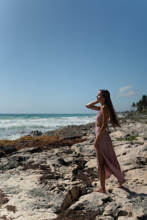 A Woman in Pink Dress Standing on the Beach