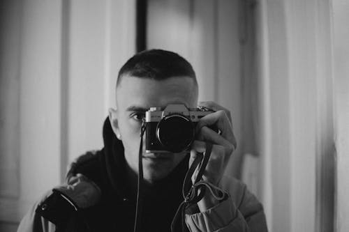 Grayscale Photo of Man Taking Picture with a Camera