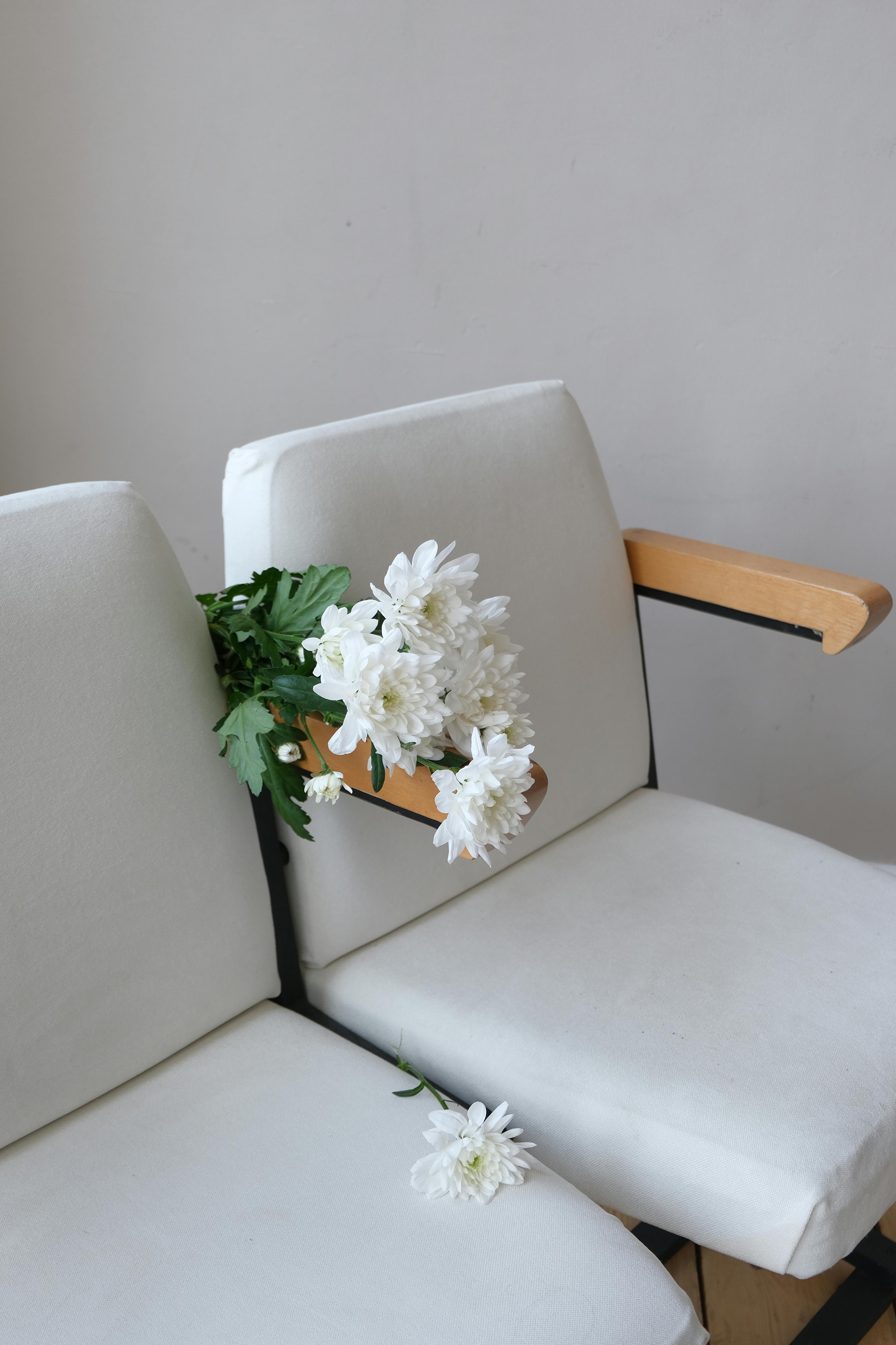 White chairs with a bouquet of flowers creating a minimalist aesthetic, perfect for a stylish interior setting.