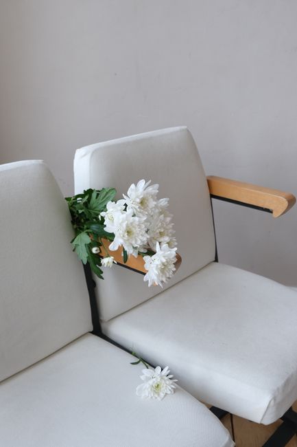 White chairs with a bouquet of flowers creating a minimalist aesthetic, perfect for a stylish interior setting.