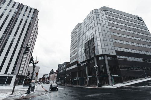Free Urban cityscape featuring modern glass buildings and cars on a wet street. Stock Photo