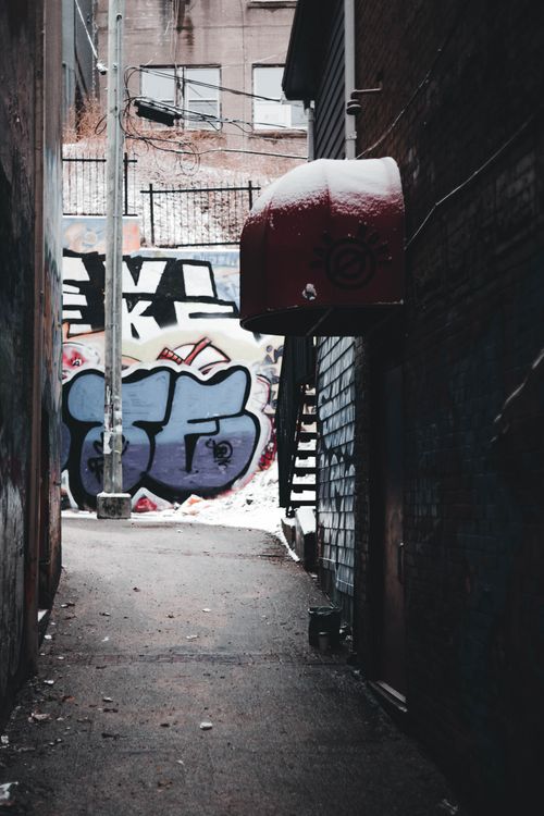 Free Narrow alleyway with colorful graffiti and snow-covered pavement. Stock Photo