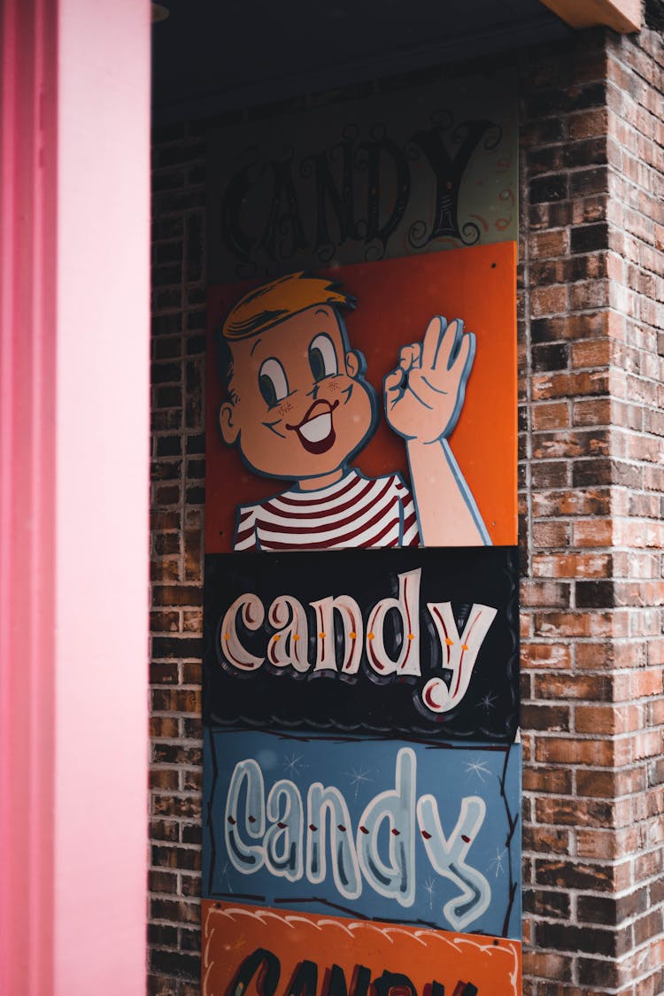 A Candy Store Signage Posted On Brick Wall