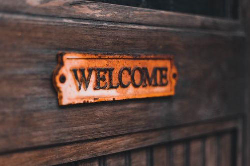 Free Close-up of a rusty vintage welcome sign on a wooden surface, creating a warm, rustic feel. Stock Photo