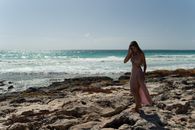 Woman in Pink Dress Standing on Rocky Shore