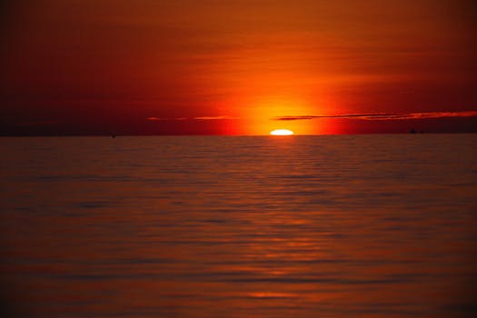Captivating sunset over a calm ocean with vibrant red and orange hues.