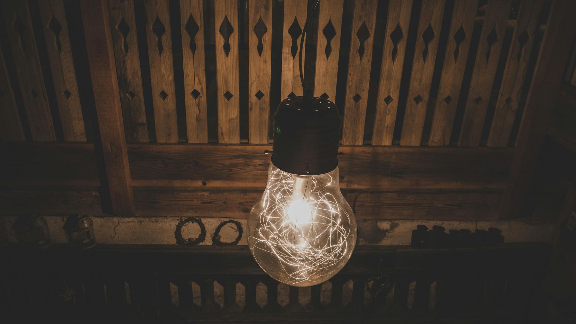 Warm glowing Edison bulb with vintage filament in a rustic wooden indoor setting.