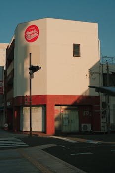 A street view of an urban corner building at dusk with music branding signage, casting long shadows.