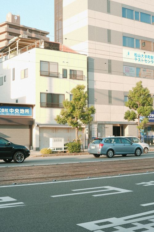 Free City street view featuring buildings and cars in bright daylight. Stock Photo
