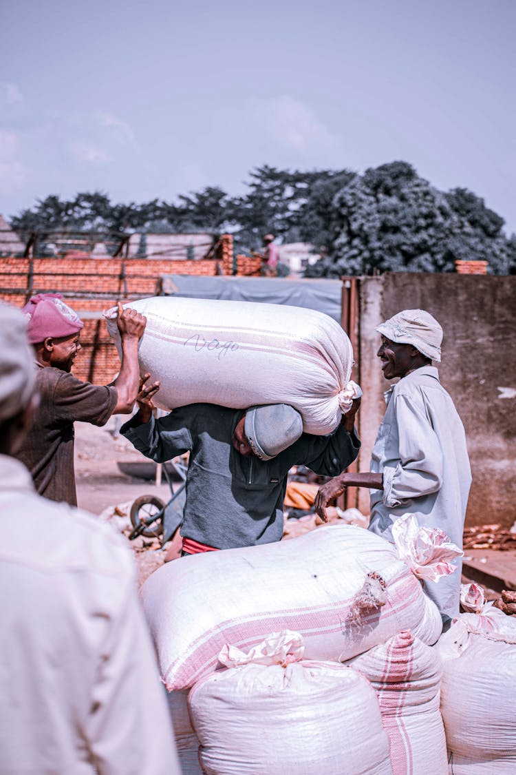 Group Of Men Carrying Heavy Bags